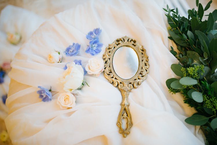 Handheld Mirror Lying On Tulle With Flowers