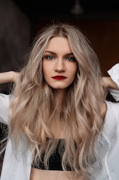 Elegant portrait of a woman with long wavy blond hair and red lipstick, showcasing natural beauty and style.