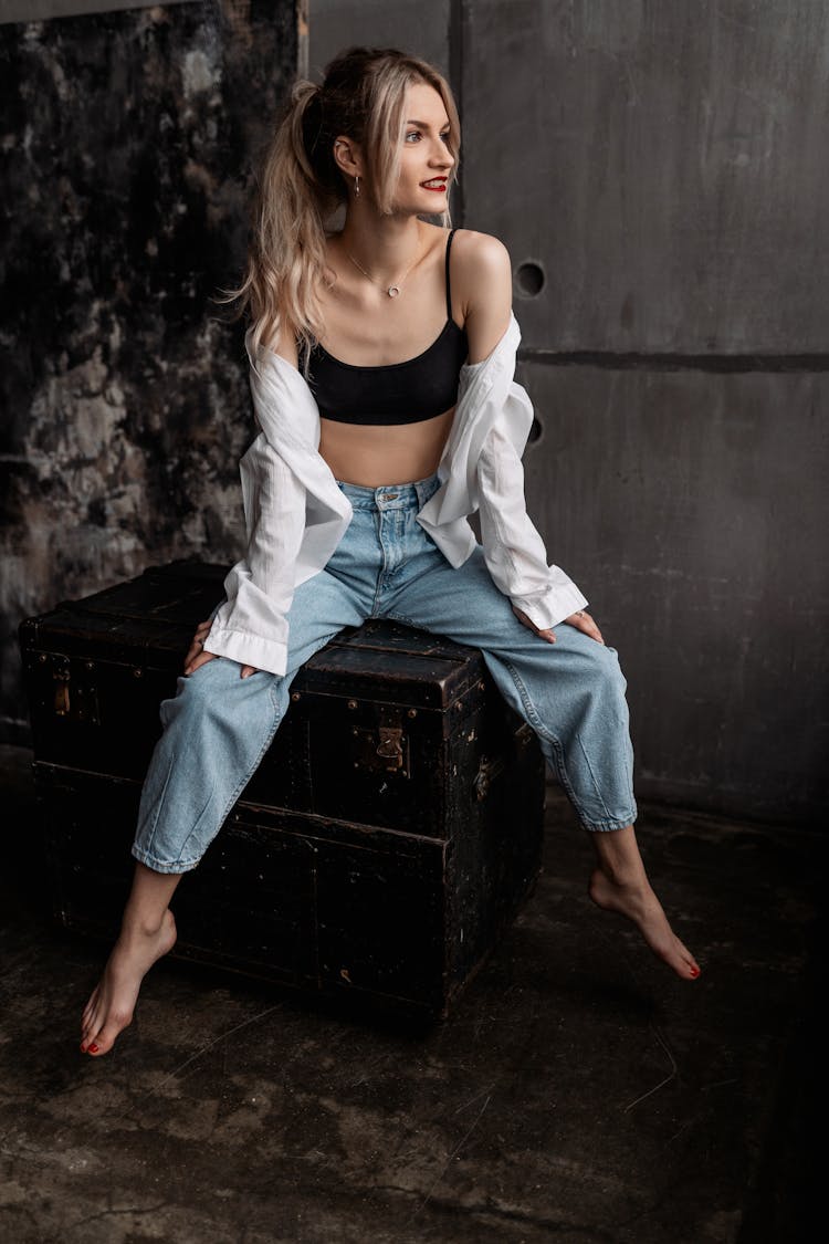 Blonde Woman Sitting In Jeans On Chest