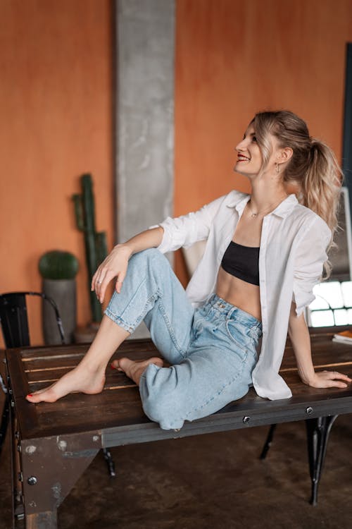 Free Blonde Woman Sitting in Jeans on Table Stock Photo