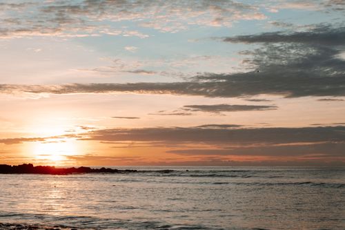 Free Peaceful ocean view at sunrise with a warm golden horizon and tranquil sea. Stock Photo