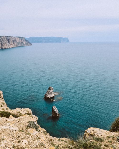 Free A breathtaking view of rocky cliffs and the expansive blue ocean under a clear sky. Stock Photo