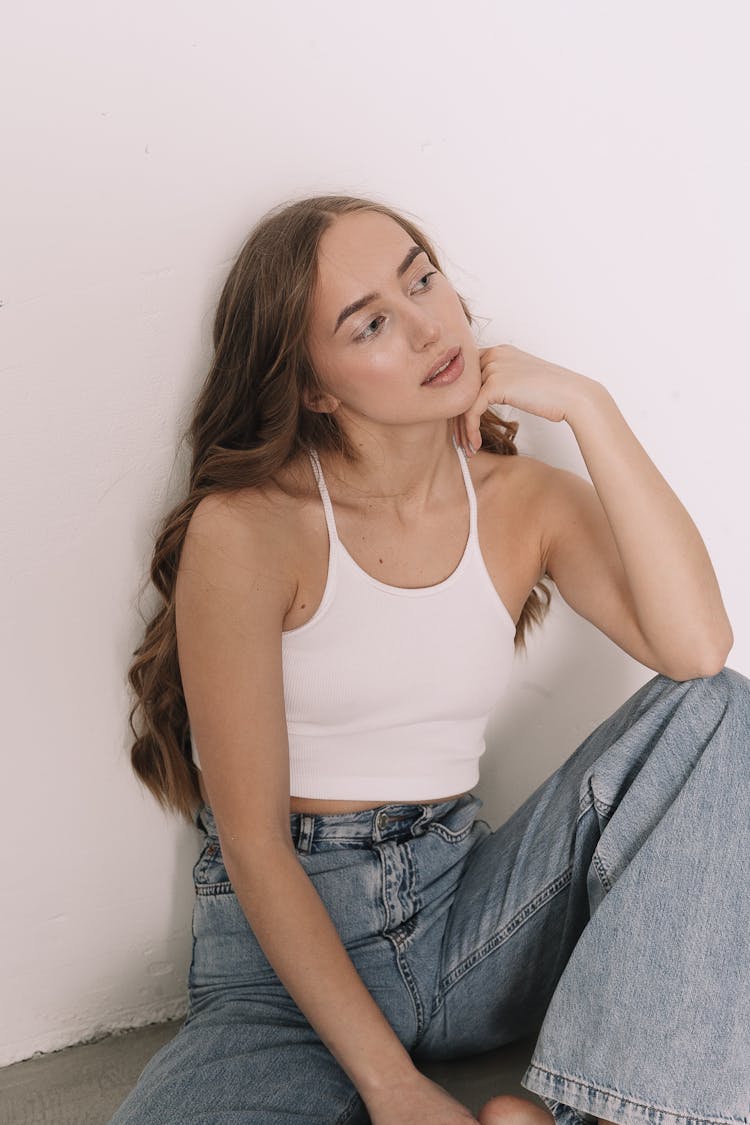 Woman Sitting In Blue Jeans And White Top