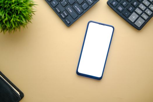 A minimalist top view of a smartphone on a desk with keyboard and plant, perfect for mockups.