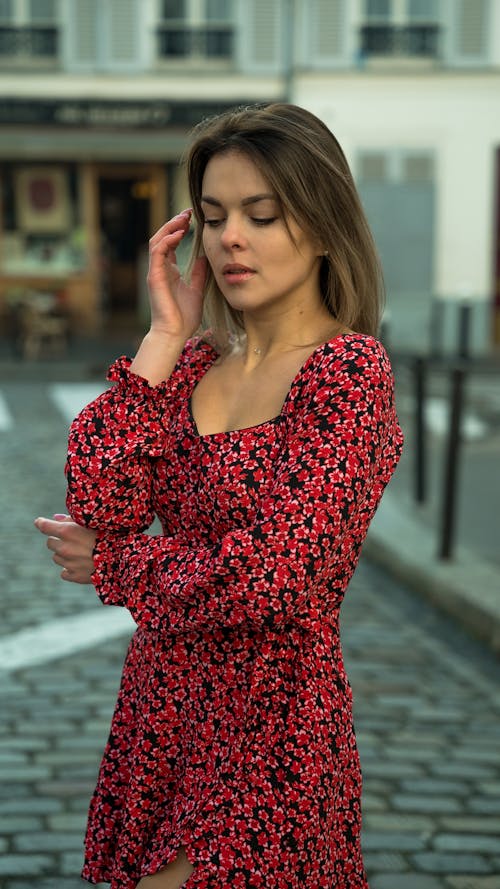 Woman in Red and Black Floral Dress Looking Down