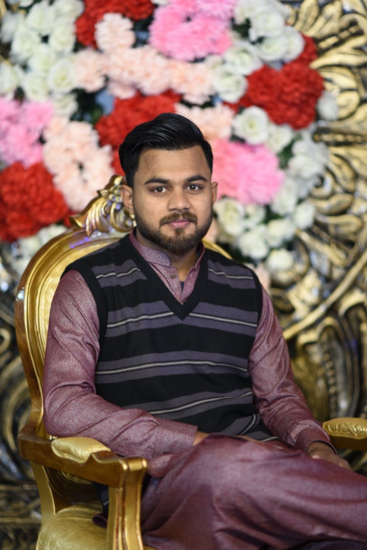 Man In Traditional Clothes Sitting In Gold Chair