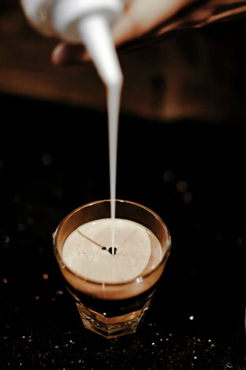 Pouring Milk in Glass with Coffee