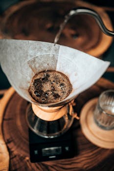 Freshly brewed pour-over coffee filtered over a glass carafe on wooden table.