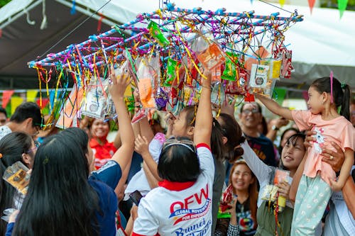 Children Playing the Pabitin Game and Reaching for Toys during a Festival on Philippines