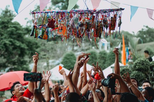 People joyfully participate in a traditional Filipino fiesta game outdoors.