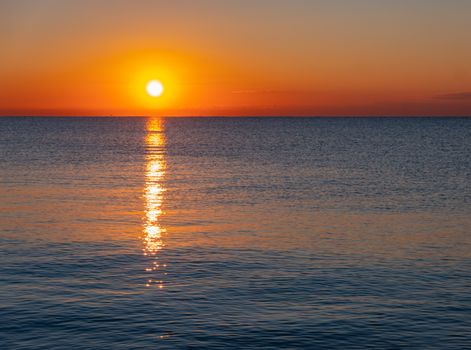 A tranquil ocean sunset with vibrant colors reflecting on the water.