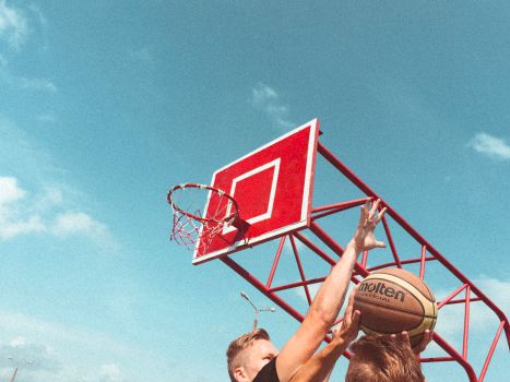 Dynamic shot of men playing basketball outdoors in Belarus under a clear blue sky.