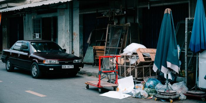 Parked car on urban street with cluttered sidewalks and old buildings in background.