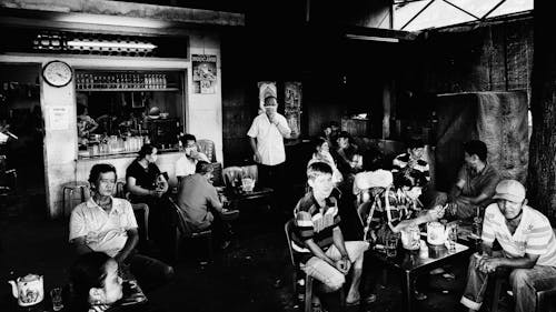 Grayscale Photo of People Sitting on Chairs