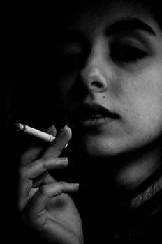 Dramatic portrait of a woman holding a cigarette, emphasizing her thoughtful expression.