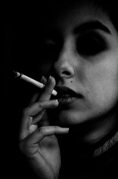 Moody black and white portrait of a woman holding a cigarette, creating a dramatic effect.