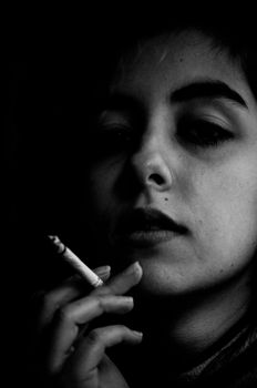 Dramatic black and white portrait of a woman smoking, capturing introspection.