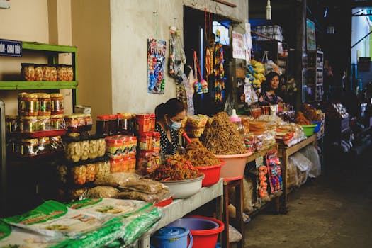 Colorful market stall displaying diverse products and a vendor in action.