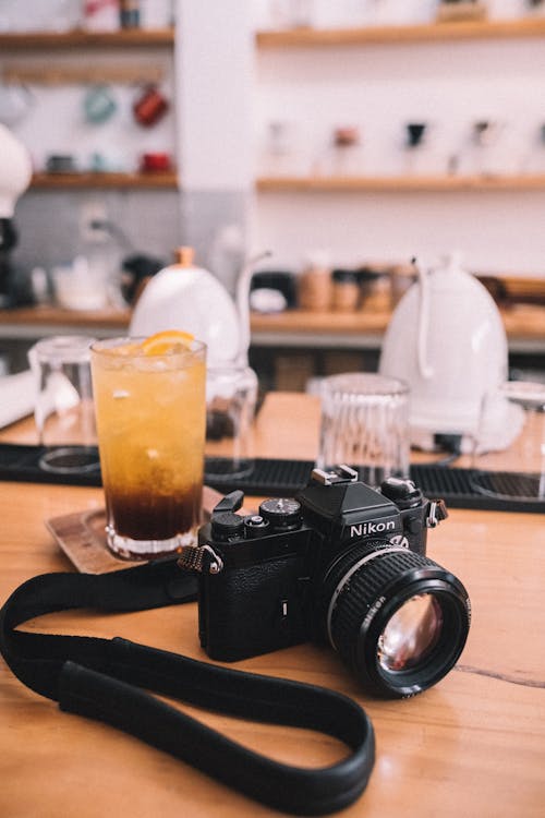 A Nikon Camera beside a Drink