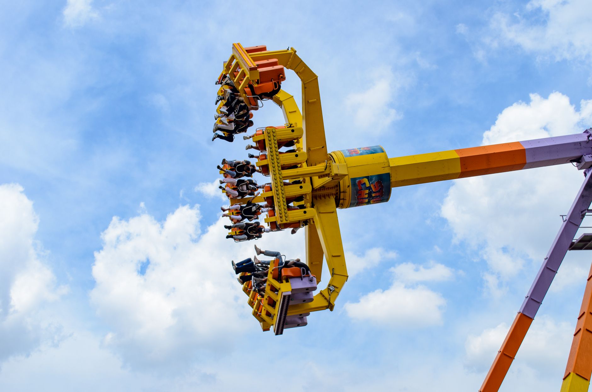 People enjoying a thrilling amusement park ride against a clear blue sky.