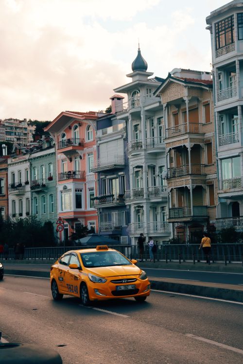 Free Colorful historic buildings line a bustling street with a moving yellow taxi in Istanbul, Turkey. Stock Photo