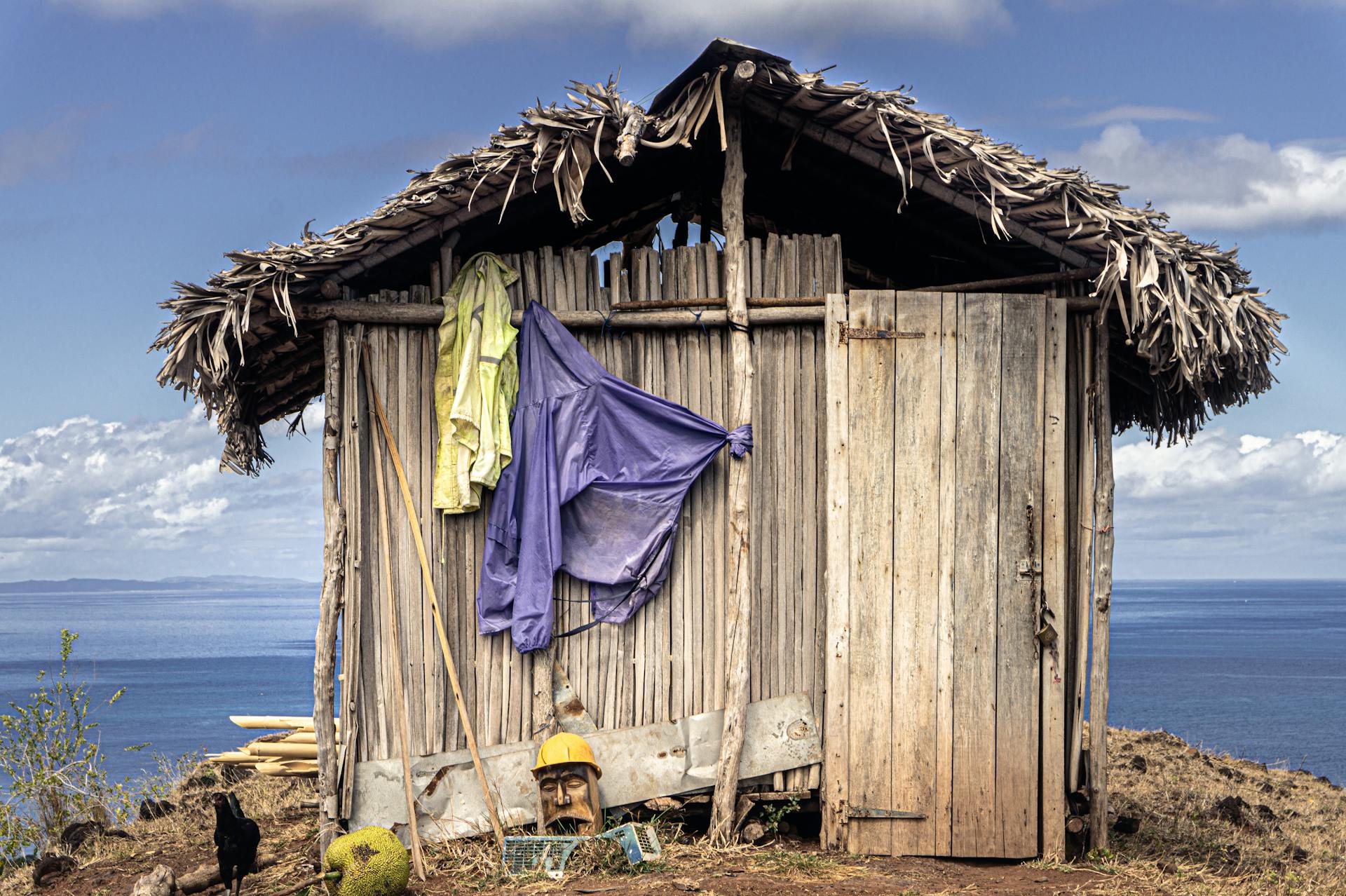 Rustic wooden hut with thatched roof and clothes near Madagascar coast, offering a scenic view.