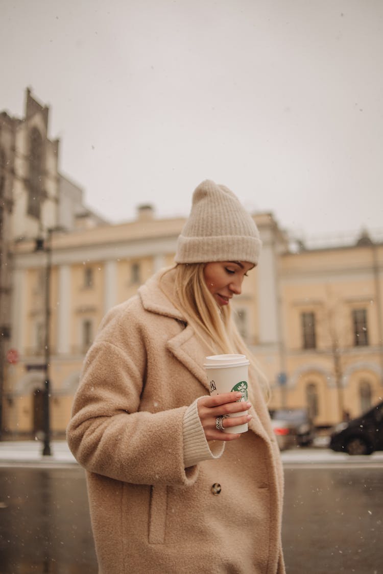 Woman Walking Through City Holding Cup Of Coffee