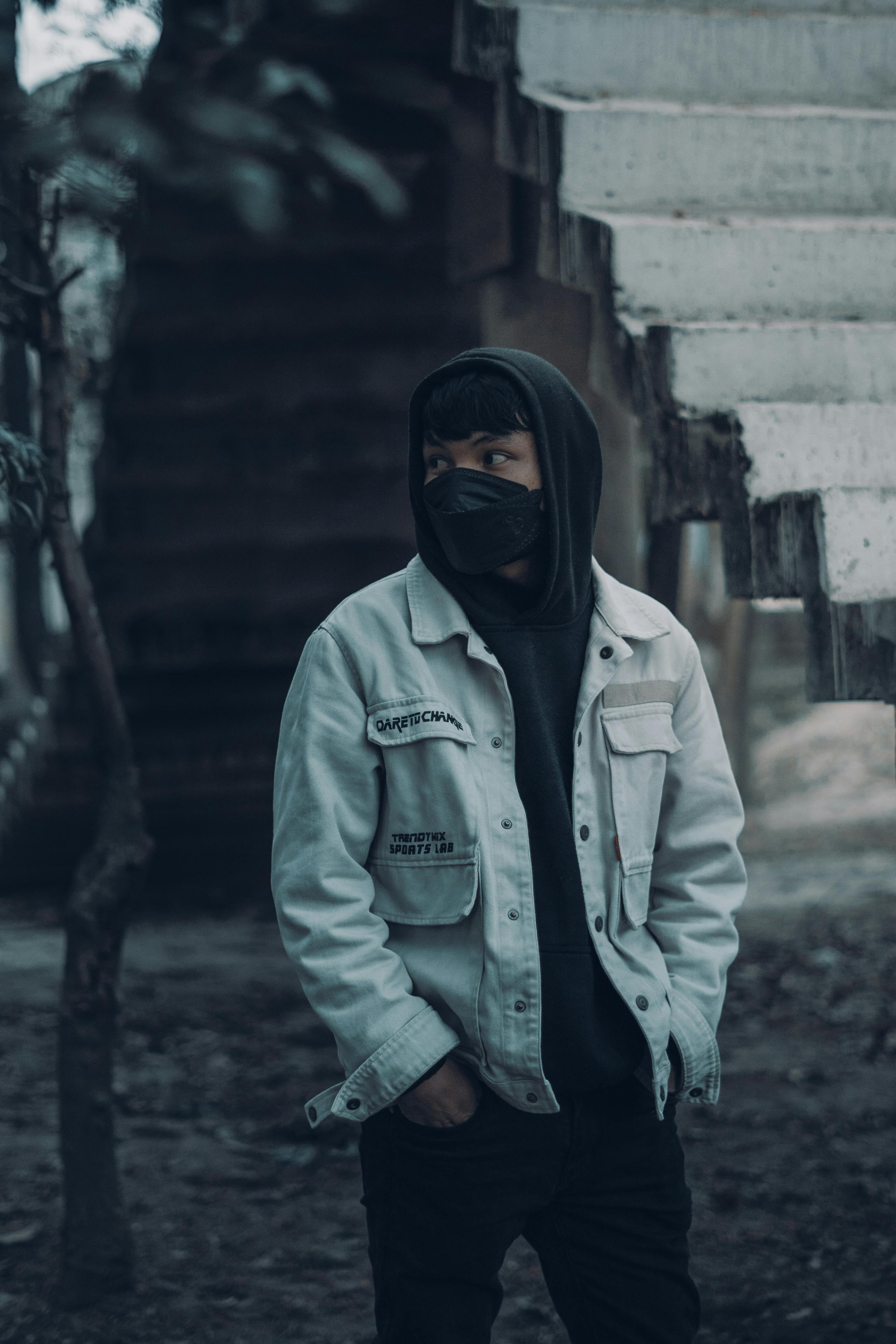 A Person in Denim Jacket Over a Hoodie Wearing Black Face Mask Free Stock Photo