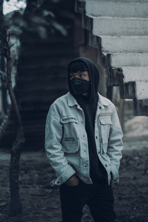 A Person in Denim Jacket Over a Hoodie Wearing Black Face Mask