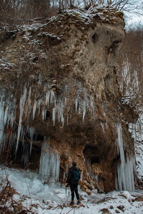 A Person Standing in Front of a Cave with Ice Formations