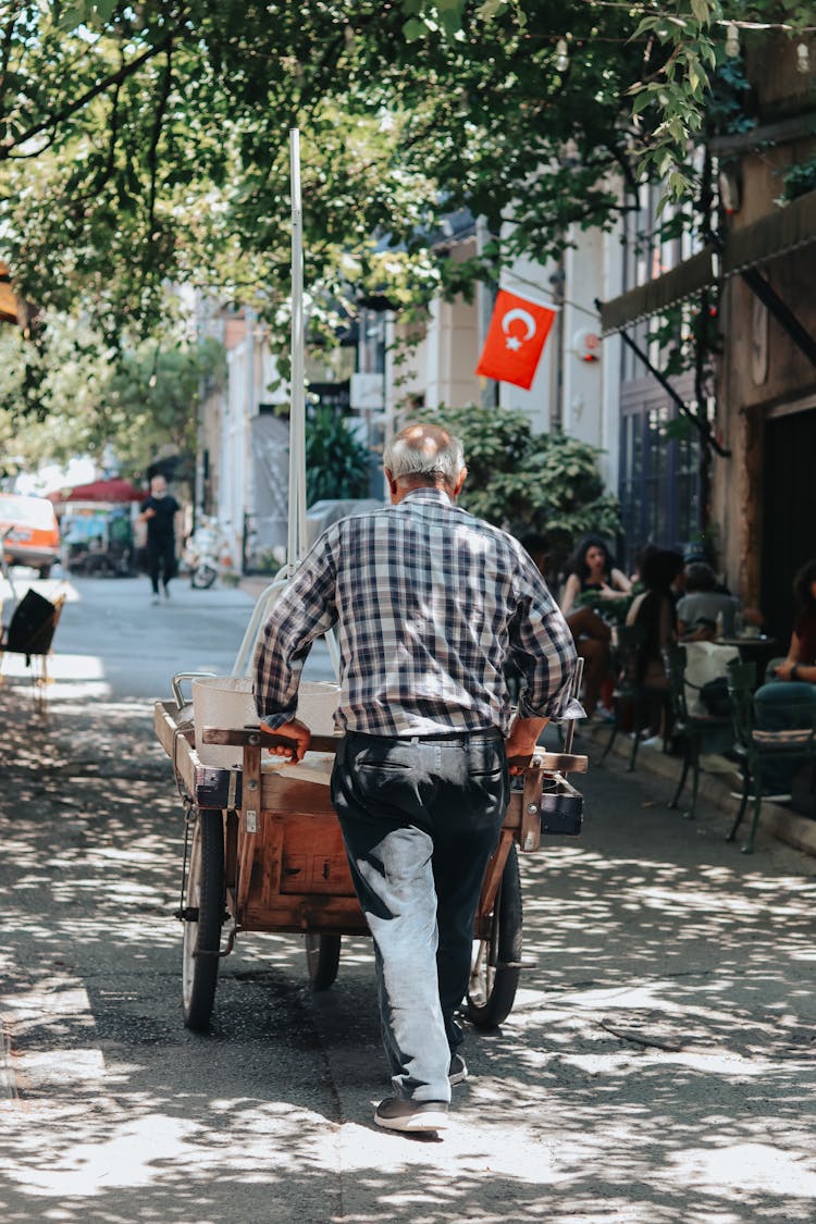 Back View Of A Person Pushing A Cart On The Road