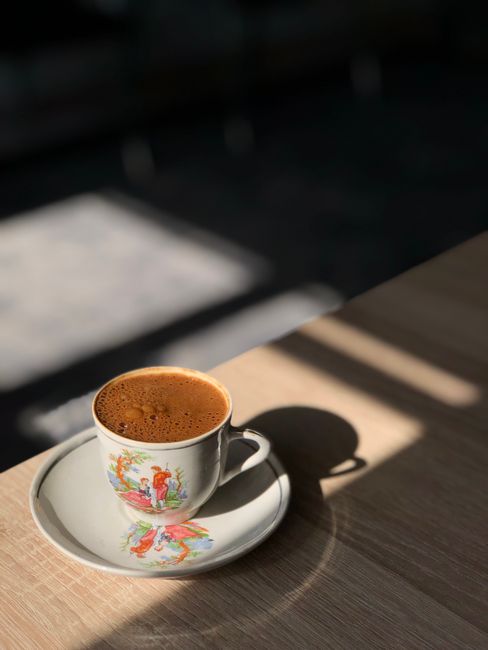 A charming cup of Turkish coffee on a wooden table, basking in sunlight.