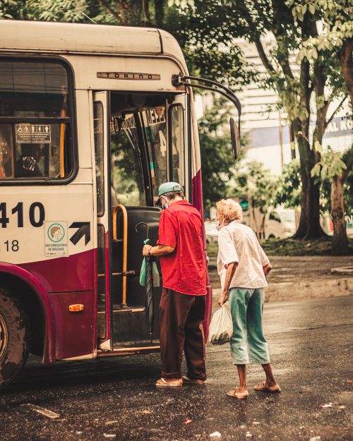 Free Two senior adults using public transportation, boarding a city bus on a rainy day. Stock Photo
