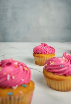 Close-up of delicious cupcakes with vibrant pink frosting and sprinkles, perfect for dessert lovers.