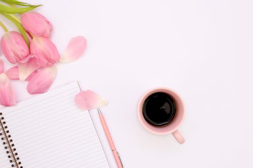 Photograph of a Cup of Coffee Near Pink Tulips