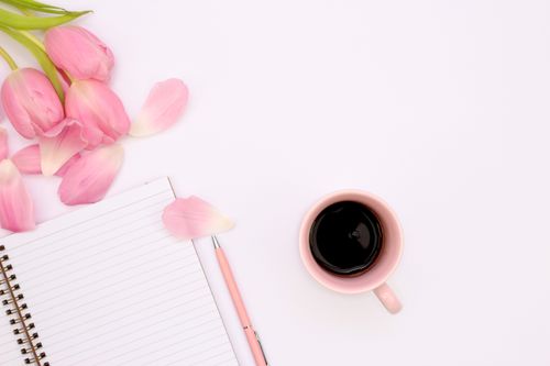 Free Aesthetic flat lay featuring a cup of coffee, pink tulips, and a spiral notebook. Stock Photo