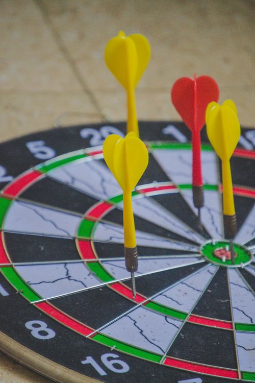 Free Colorful darts hitting the bullseye on a dartboard, capturing precision and focus. Stock Photo