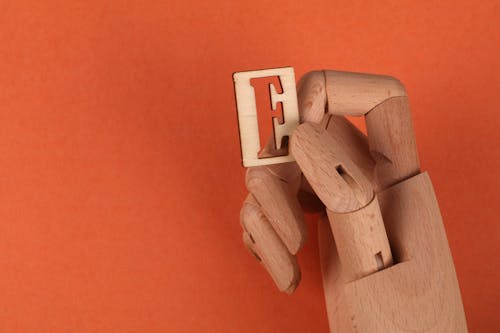 A Wooden Hand Holding a Wooden Letter E