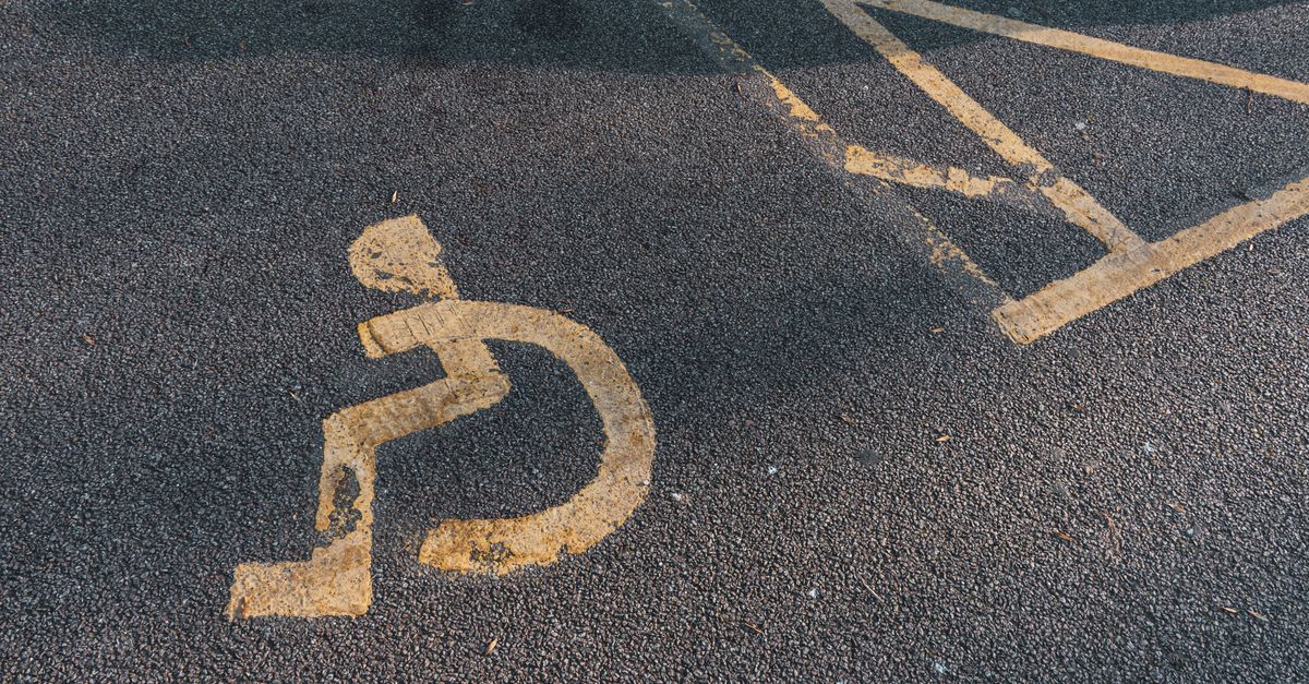A faded disabled parking symbol painted on asphalt pavement, highlighting accessibility.