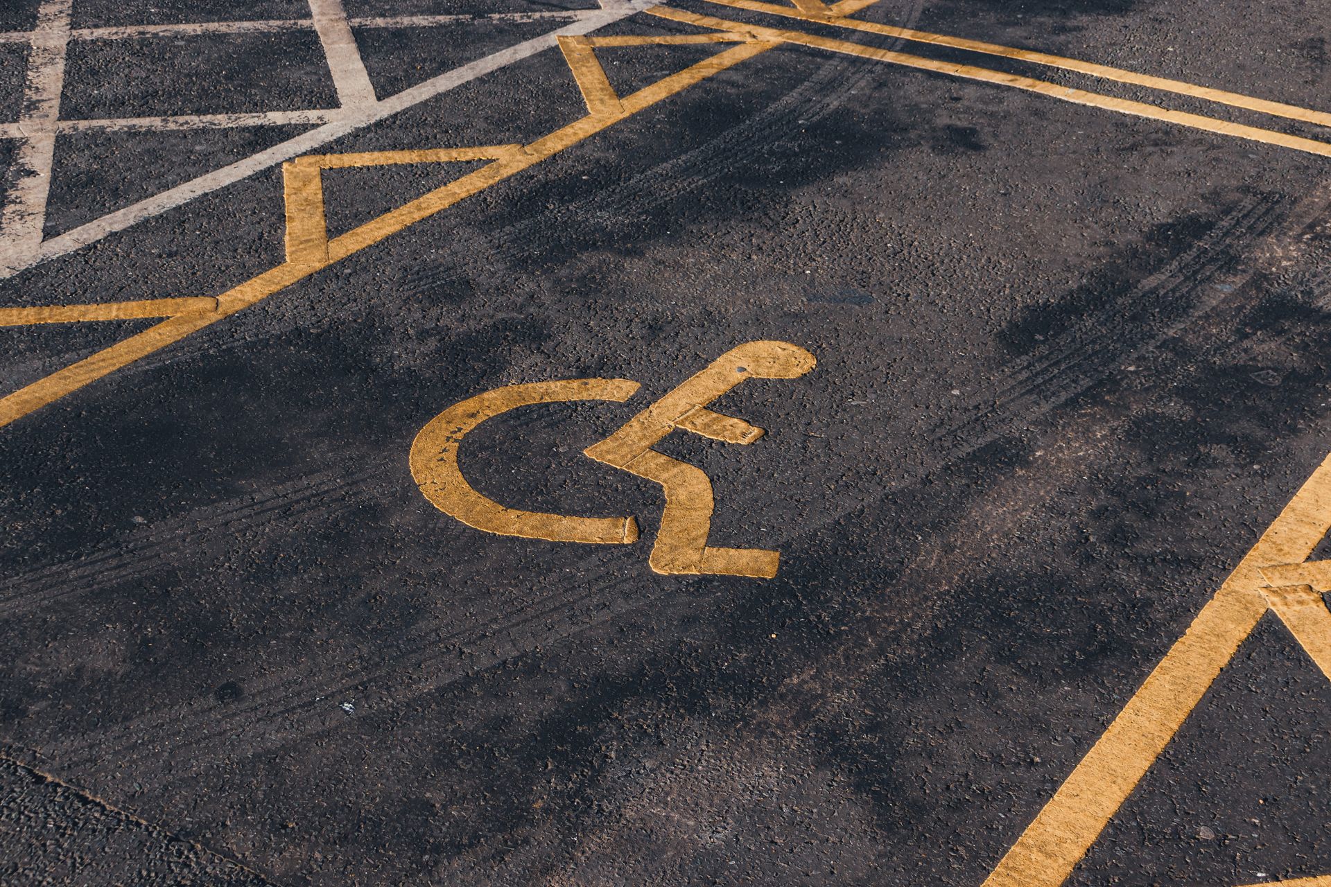 Close-up view of an international accessibility symbol painted on a parking lot surface.