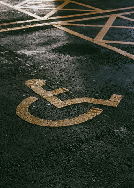 Vertical shot of a painted handicap symbol on asphalt, with textured pavement. Vertical shot of a painted handicap symbol on asphalt, with textured pavement.