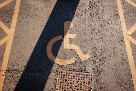 Close-up of a yellow wheelchair symbol painted on asphalt, highlighting accessibility.