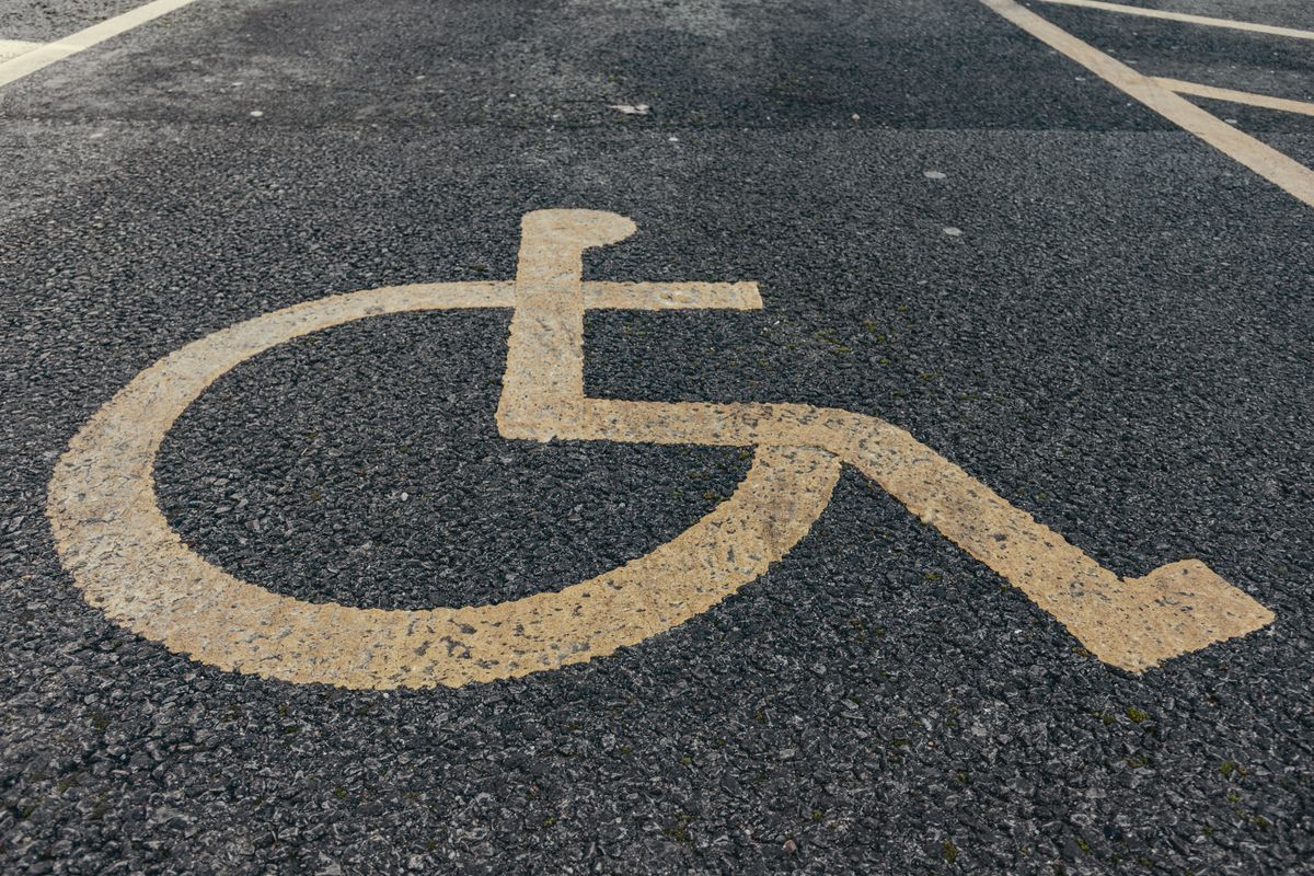 Worn accessibility symbol painted on an existing parking surface