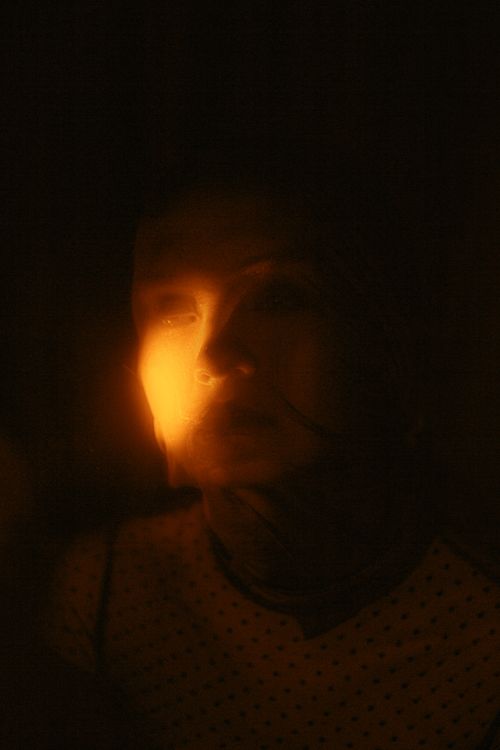 Free A mysterious portrait of a woman illuminated by warm, focused light, invoking intrigue. Stock Photo