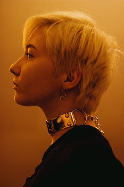 Profile portrait of a woman with short blonde hair and jewelry in warm sunset lighting.
