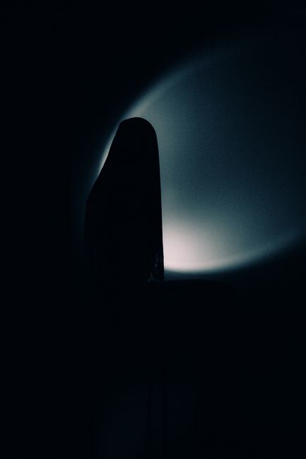 A dark silhouette of a figure against a moody, shadowy background.