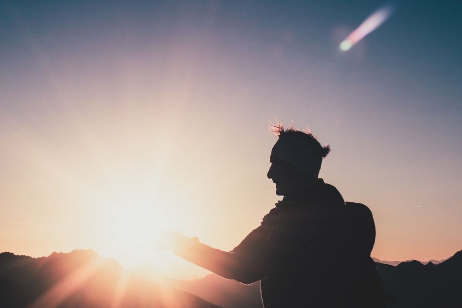 A lone hiker silhouetted against a vibrant sunrise atop a mountain, capturing the essence of adventure.