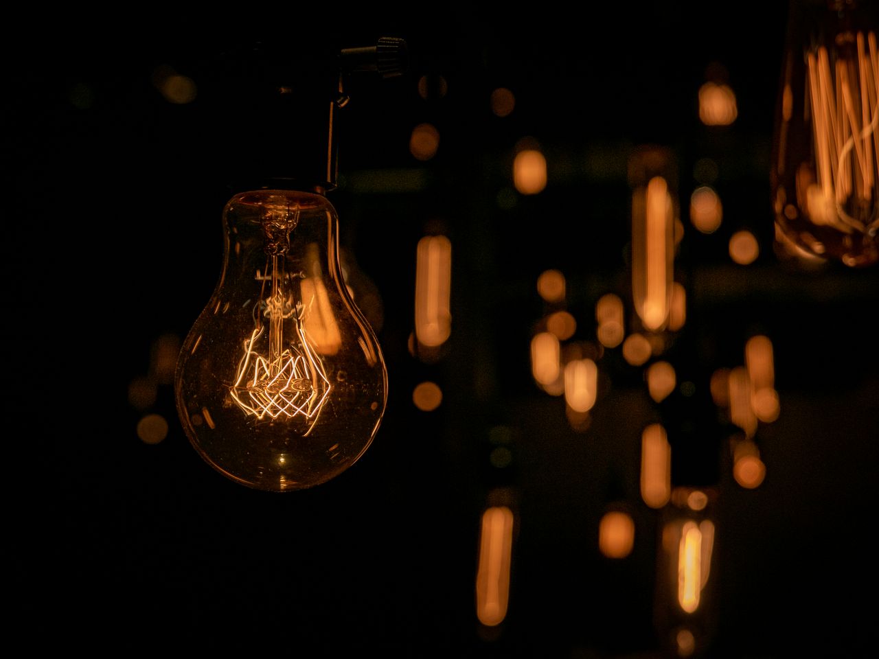 warm glow of vintage light bulbs hanging in a dark setting creating an
