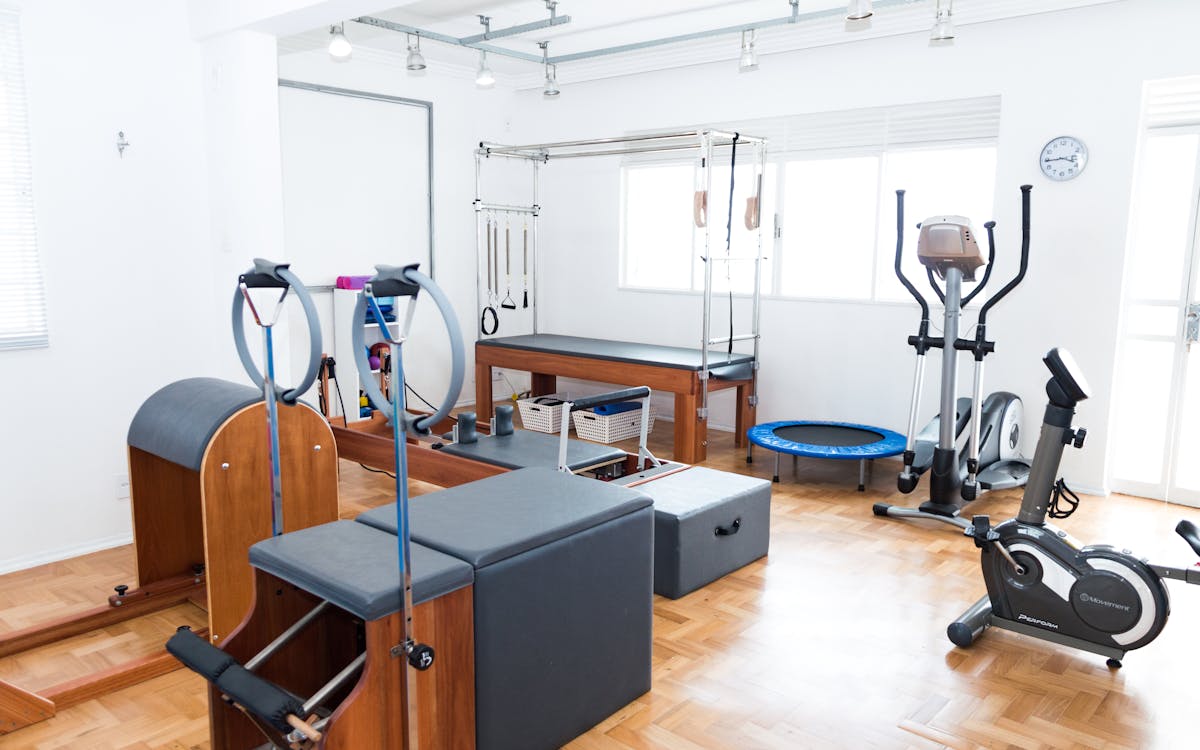 Bright gym space featuring Pilates equipment, exercise bikes, and wooden flooring for a modern workout experience.