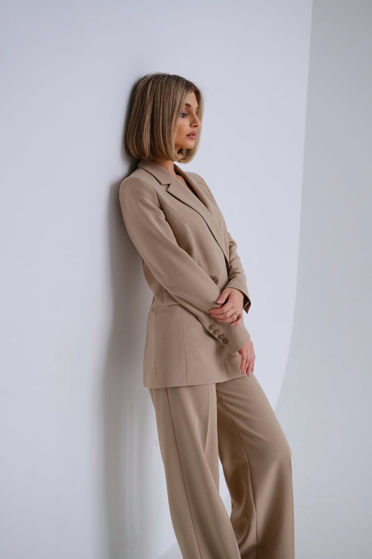 Woman In Tan Coat Leaning Against Wall